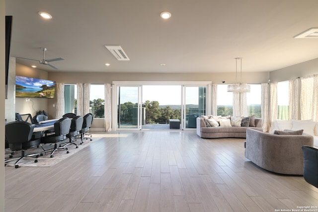 living room featuring light wood-type flooring and ceiling fan with notable chandelier