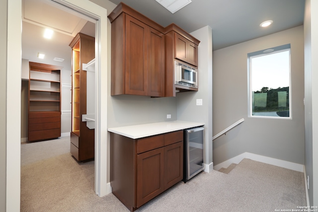 kitchen featuring beverage cooler, light carpet, and stainless steel microwave