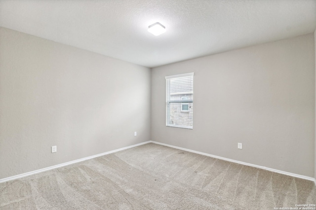 empty room with a textured ceiling and light colored carpet