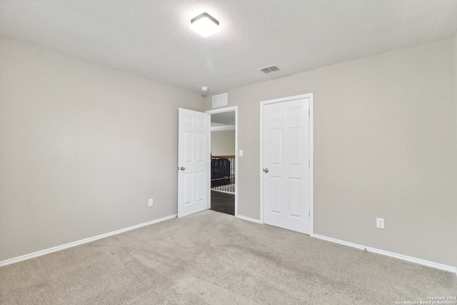 unfurnished bedroom with a textured ceiling and carpet floors