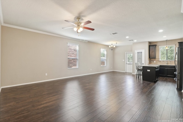 living room featuring dark wood-type flooring, ceiling fan with notable chandelier, crown molding, and sink