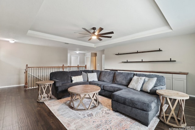 living room with a tray ceiling, dark hardwood / wood-style flooring, and ceiling fan