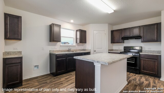 kitchen featuring black gas range oven, a kitchen island, dark hardwood / wood-style floors, and dark brown cabinetry