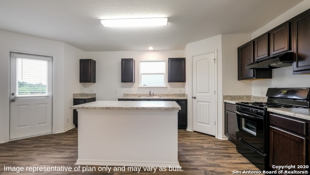 kitchen with a center island, dark wood-type flooring, sink, black gas range oven, and dark brown cabinetry