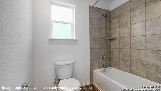 bathroom featuring toilet and tiled shower / bath