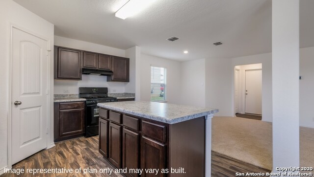 kitchen with black gas stove, a kitchen island, dark brown cabinets, and dark hardwood / wood-style flooring