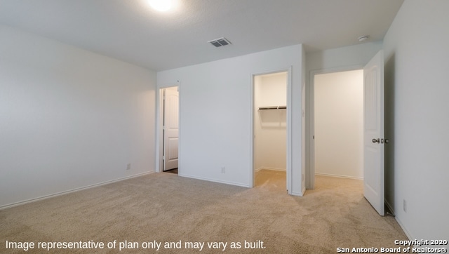 unfurnished bedroom with a walk in closet, light carpet, and a closet