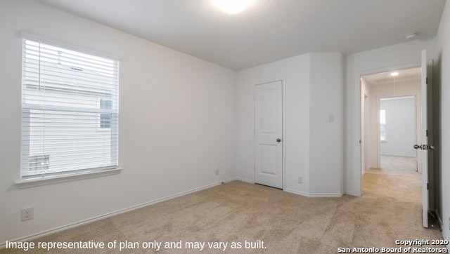 unfurnished bedroom featuring light colored carpet and multiple windows