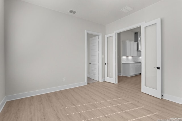 unfurnished bedroom with french doors and light wood-type flooring