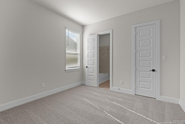 unfurnished bedroom featuring ensuite bath and light colored carpet