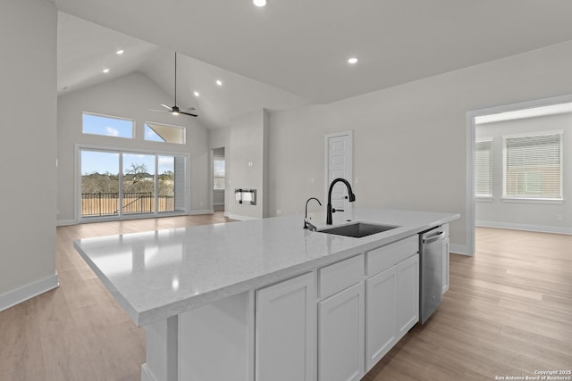 kitchen featuring sink, white cabinetry, light stone counters, a center island with sink, and stainless steel dishwasher