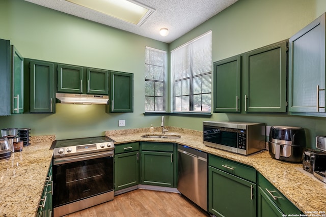 kitchen featuring light wood-type flooring, green cabinets, appliances with stainless steel finishes, and sink