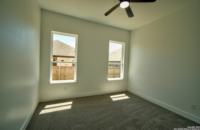 spare room featuring dark colored carpet and ceiling fan