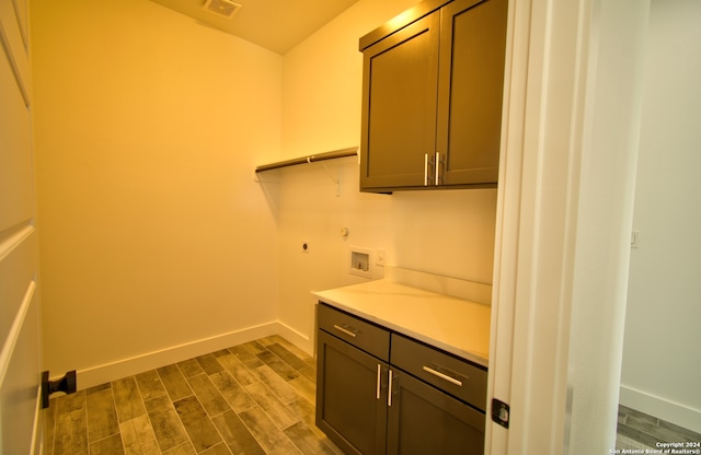 washroom featuring washer hookup, hookup for an electric dryer, dark wood-type flooring, and cabinets