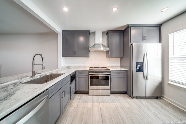 kitchen with plenty of natural light, stainless steel appliances, wall chimney exhaust hood, and sink