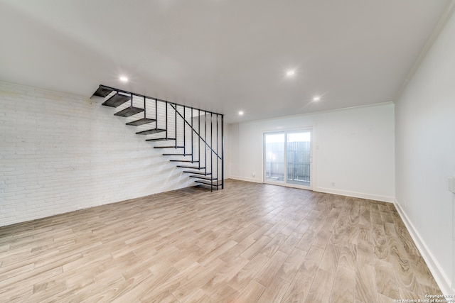 interior space with brick wall, light hardwood / wood-style floors, and ornamental molding