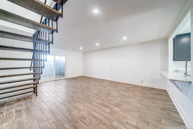 unfurnished living room with crown molding and light hardwood / wood-style floors