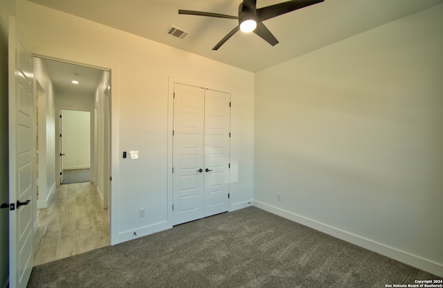 unfurnished bedroom featuring ceiling fan, a closet, and carpet flooring