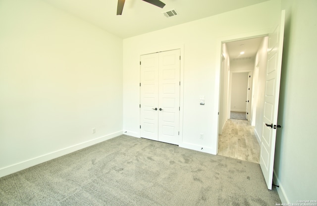 unfurnished bedroom featuring ceiling fan, light colored carpet, and a closet