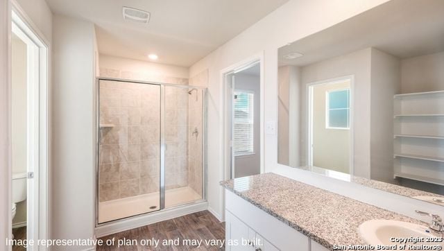 bathroom featuring hardwood / wood-style flooring, vanity, and a shower with shower door