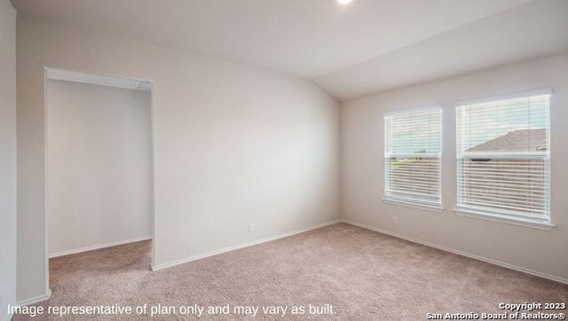 carpeted spare room with vaulted ceiling