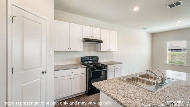 kitchen featuring light stone countertops, black gas range oven, dark wood-type flooring, sink, and white cabinetry