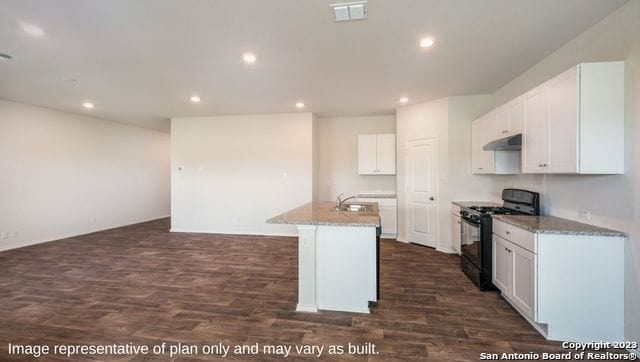 kitchen featuring light stone countertops, black gas range oven, dark hardwood / wood-style floors, a kitchen island with sink, and white cabinets