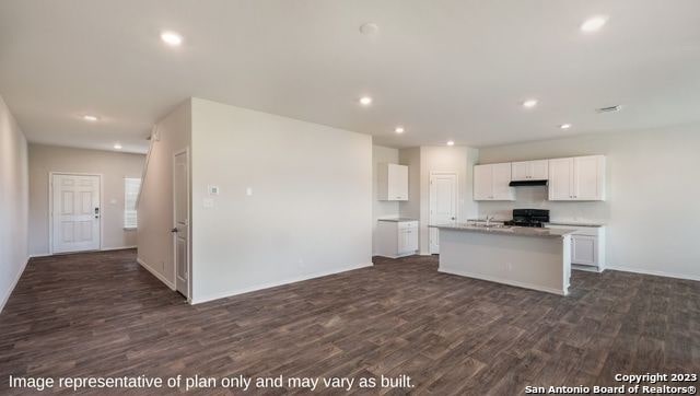 kitchen featuring white cabinetry, a kitchen island with sink, black range, and dark hardwood / wood-style floors