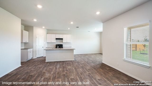 kitchen featuring black range oven, white cabinetry, a kitchen island with sink, and dark wood-type flooring