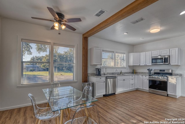 kitchen featuring light hardwood / wood-style flooring, ceiling fan, appliances with stainless steel finishes, and white cabinets