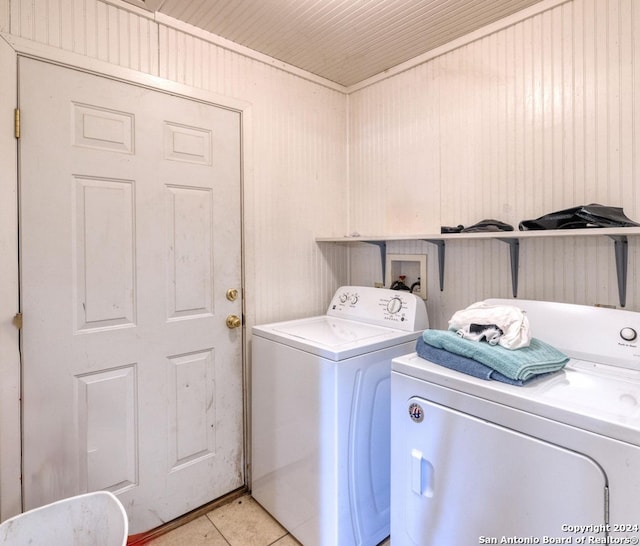 clothes washing area featuring washing machine and dryer, wood walls, and light tile patterned flooring