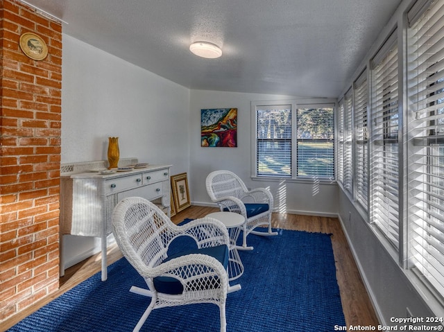 living area featuring lofted ceiling, hardwood / wood-style flooring, and a textured ceiling