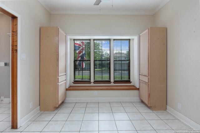 empty room featuring ceiling fan, ornamental molding, and light tile patterned floors