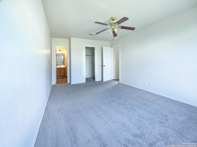 unfurnished bedroom featuring ensuite bath, a closet, carpet floors, baseboards, and ceiling fan