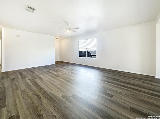 spare room featuring dark wood finished floors, visible vents, baseboards, and a ceiling fan