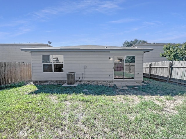 rear view of property featuring a yard, cooling unit, and a fenced backyard