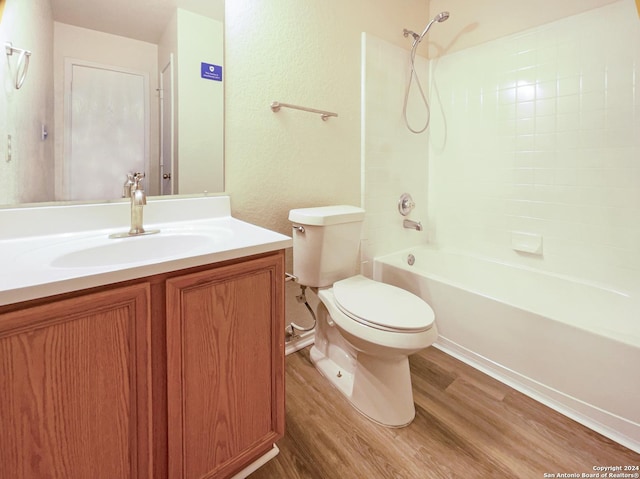 bathroom featuring toilet, shower / tub combination, wood finished floors, vanity, and a textured wall