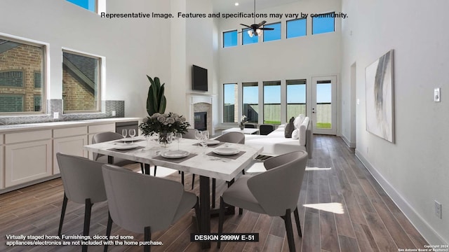 dining room with a high ceiling, ceiling fan, a fireplace, and dark hardwood / wood-style floors