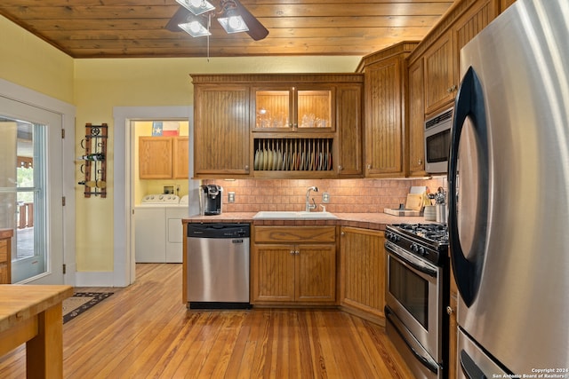 kitchen with light hardwood / wood-style flooring, backsplash, washing machine and clothes dryer, stainless steel appliances, and sink