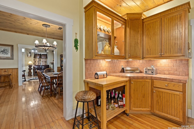 kitchen featuring wood ceiling, light hardwood / wood-style floors, a notable chandelier, pendant lighting, and tasteful backsplash