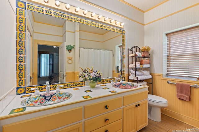 full bath with wallpapered walls, toilet, a wainscoted wall, and a sink