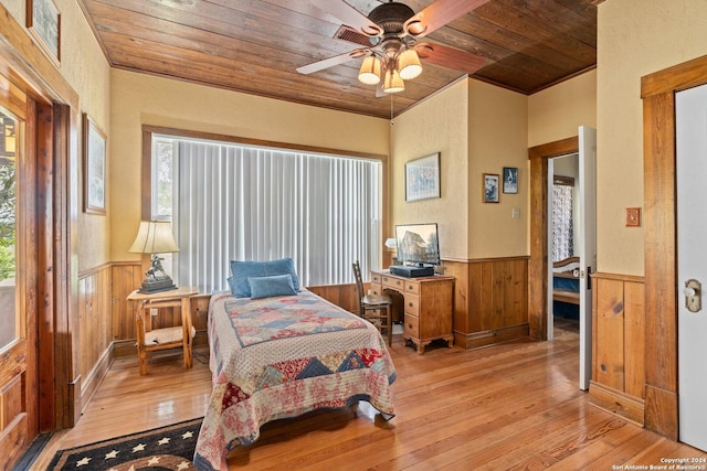 bedroom featuring light wood finished floors, a wainscoted wall, wood ceiling, and wooden walls