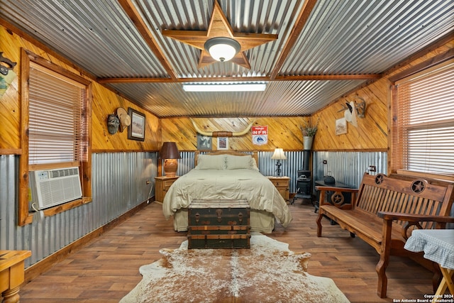 bedroom featuring cooling unit, wood walls, ceiling fan, and hardwood / wood-style flooring