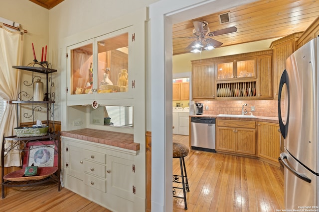 kitchen featuring independent washer and dryer, tile countertops, light hardwood / wood-style flooring, stainless steel appliances, and sink