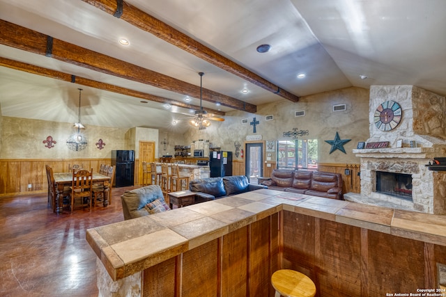 living room with ceiling fan, a fireplace, and vaulted ceiling with beams