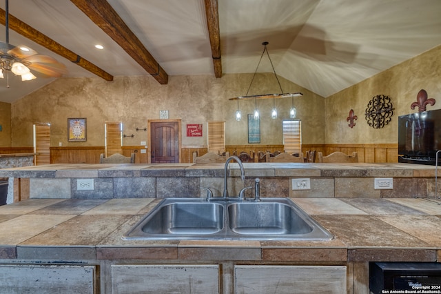 kitchen with lofted ceiling with beams, sink, ceiling fan, and pendant lighting