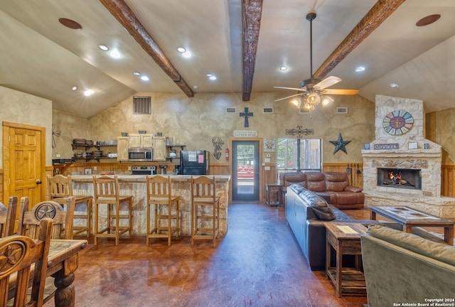 living room with ceiling fan, vaulted ceiling with beams, and a fireplace