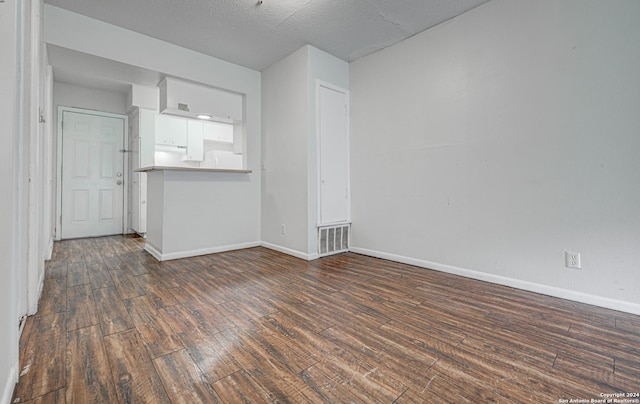 empty room featuring visible vents, a textured ceiling, baseboards, and wood finished floors