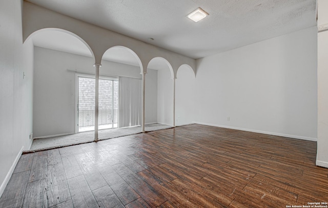 empty room with baseboards, a textured ceiling, and wood finished floors