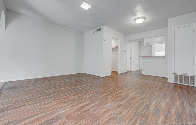 unfurnished living room with wood finished floors, visible vents, and baseboards